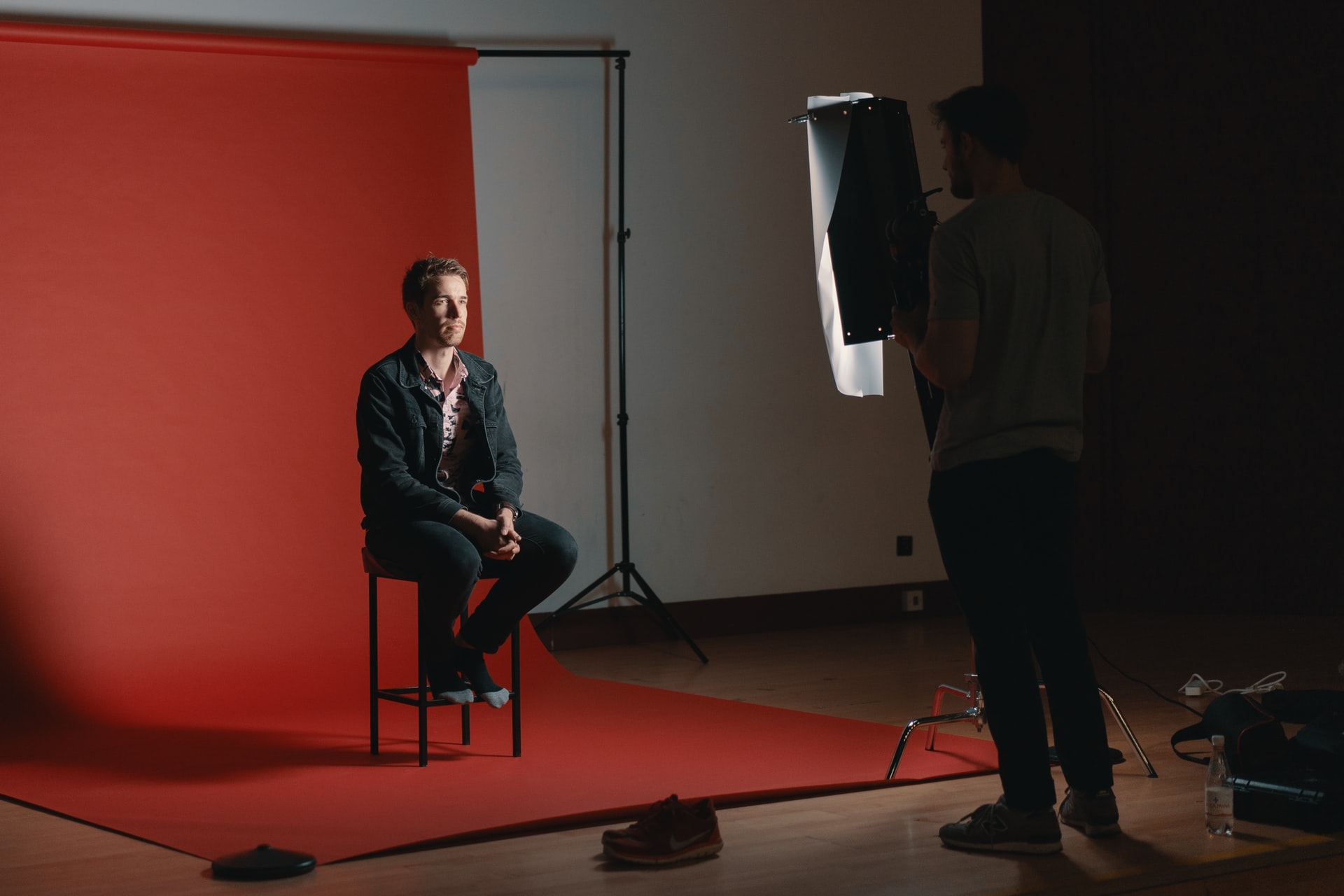 leverage business headshots; a person getting their headshot taken in a studio, against a red background