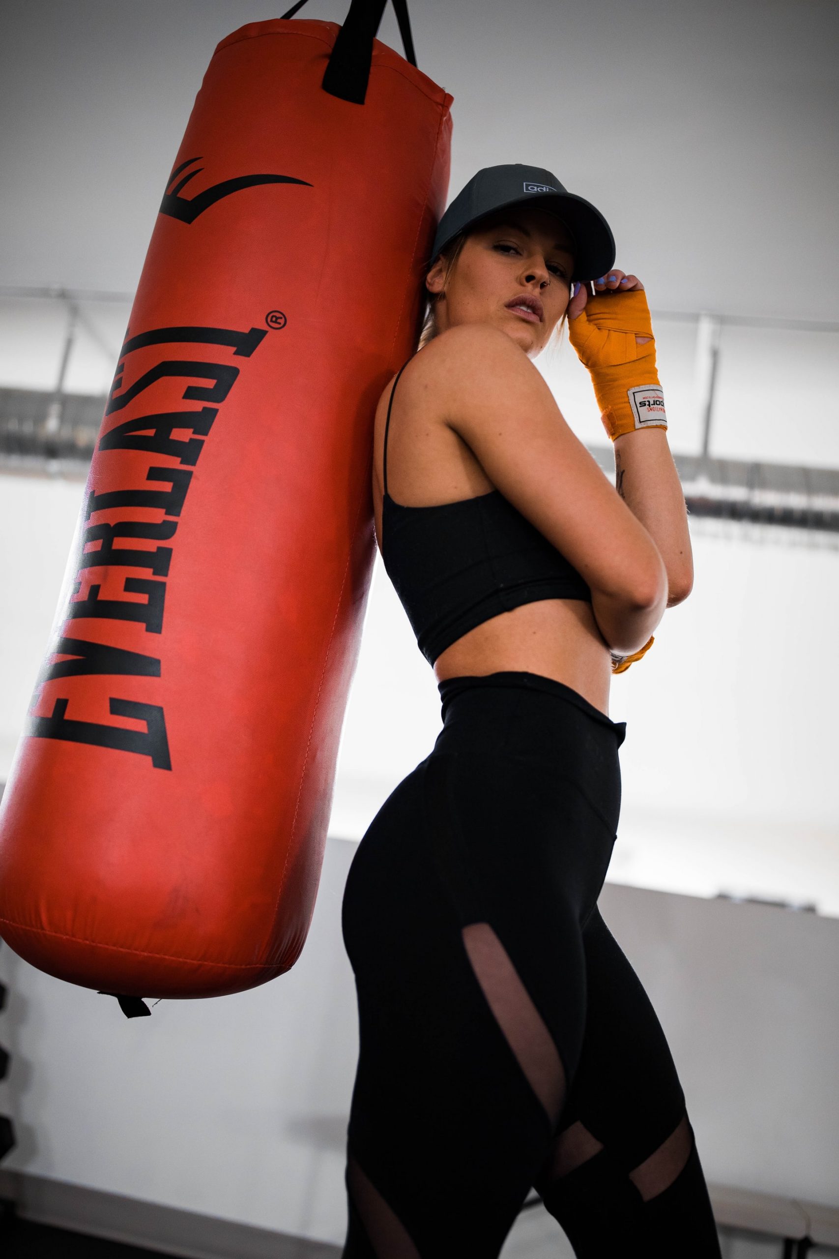 Fitness Photoshoot; A Fitness model posing against a punching bag for the camera.
