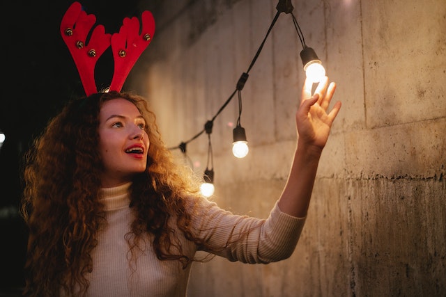 Christmas product photography, a woman wearing Christmas gear and posing with lights